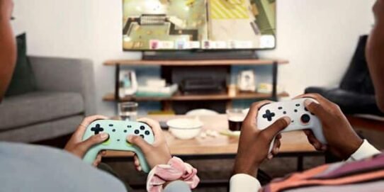 Deux personnes jouent à un jeu vidéo sur console dans un salon