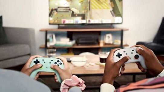 Deux personnes jouent à un jeu vidéo sur console dans un salon