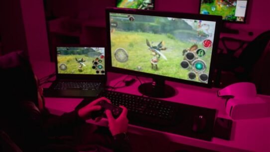 Personne jouant à un jeu vidéo sur un écran d'ordinateur dans une pièce sombre