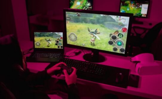 Personne jouant à un jeu vidéo sur un écran d'ordinateur dans une pièce sombre