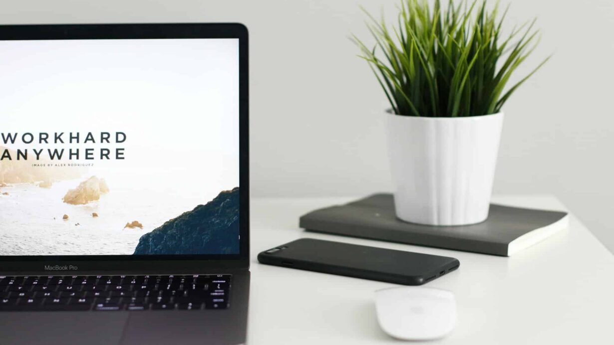 Ordinateur portable et plante sur un bureau blanc