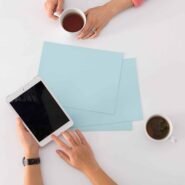 Deux mains avec café et tablette sur une table blanche