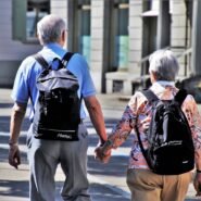 Couple de seniors avec sacs à dos marchant en ville main dans la main