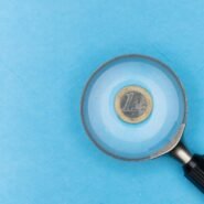 Pièce d'un euro observée à travers une loupe sur fond bleu