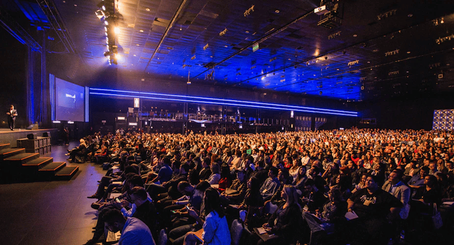 Une foule assiste à une conférence dans une salle illuminée