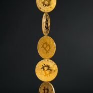 Cinq pièces de Bitcoin tombant verticalement sur fond noir