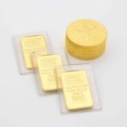 Trois lingots d'or et une pile de pièces sur fond blanc