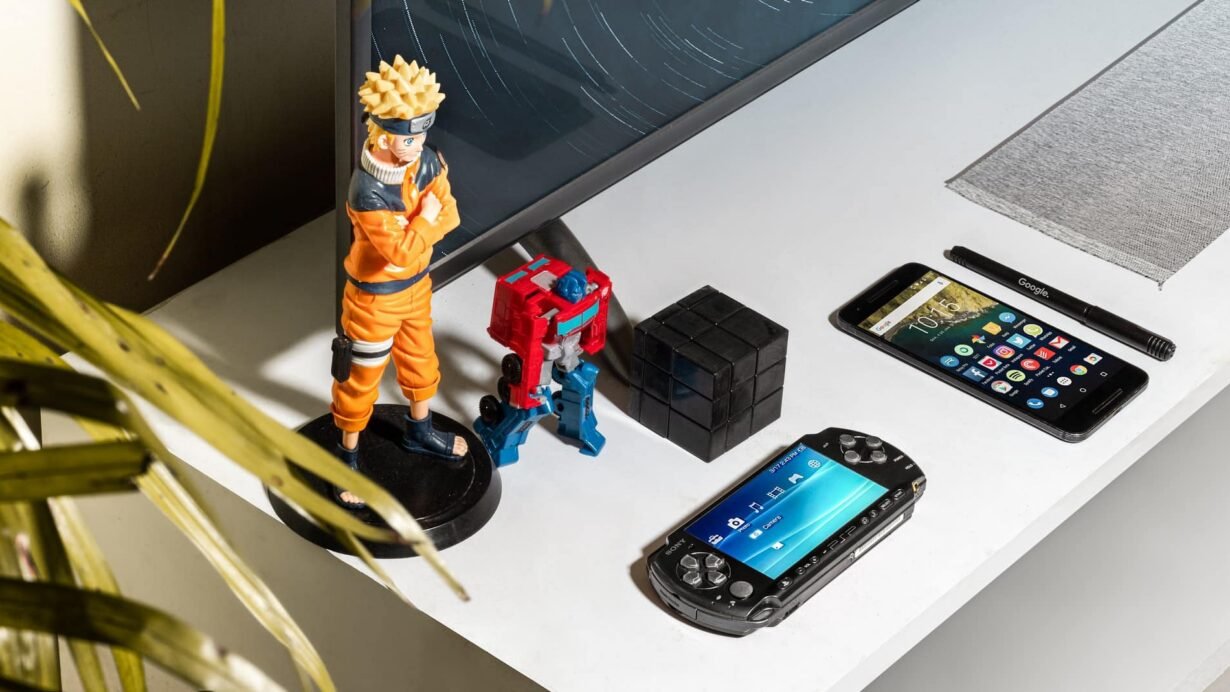 Figurines, smartphone et console sur un bureau blanc