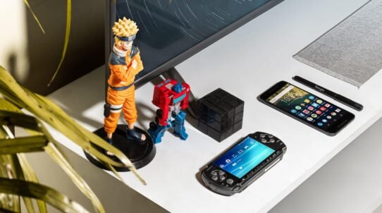 Figurines, smartphone et console sur un bureau blanc