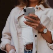 Femme en veste beige tenant un smartphone