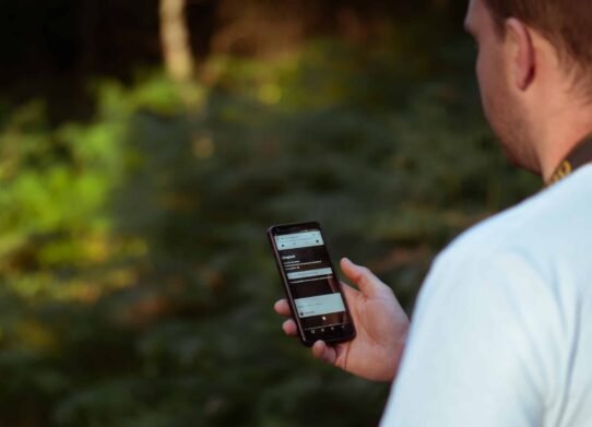 Personne tenant un smartphone avec une forêt en arrière-plan