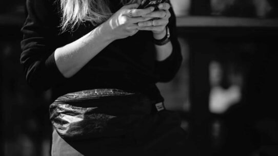 Femme tenant un smartphone avec une banane à la taille