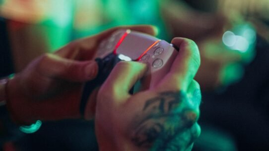 Main tenant une manette de jeu avec fond lumineux