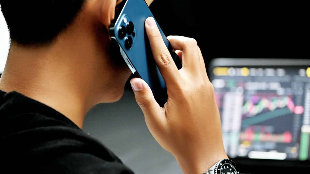 Personne au téléphone devant un écran d'ordinateur avec graphiques