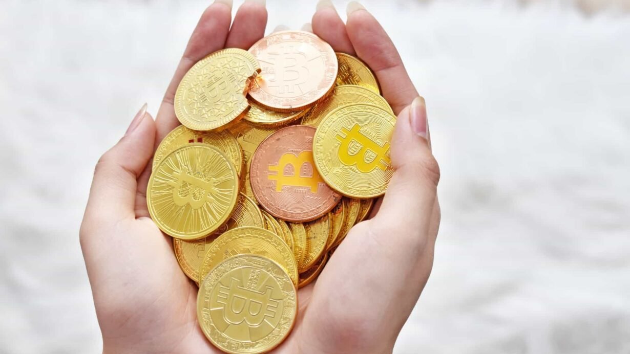 Mains avec des pièces de bitcoin dorées et cuivrées