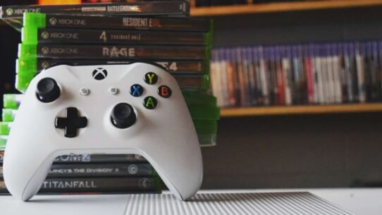 Manette Xbox blanche avec jeux vidéo en arrière-plan