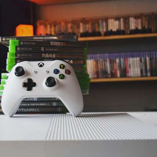 Manette Xbox blanche avec jeux vidéo en arrière-plan