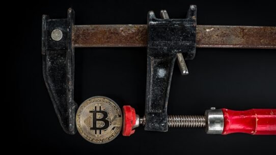 Pièce de Bitcoin serrée dans un étau en métal