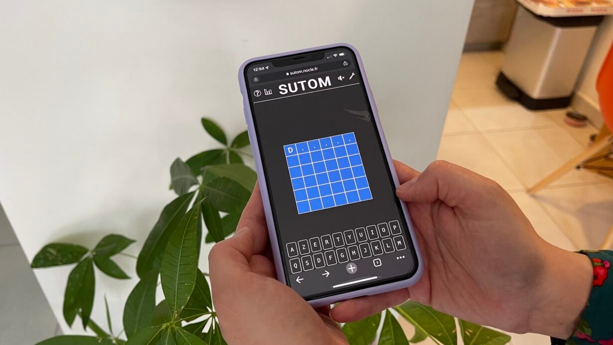 Personne jouant à SUTOM sur un téléphone