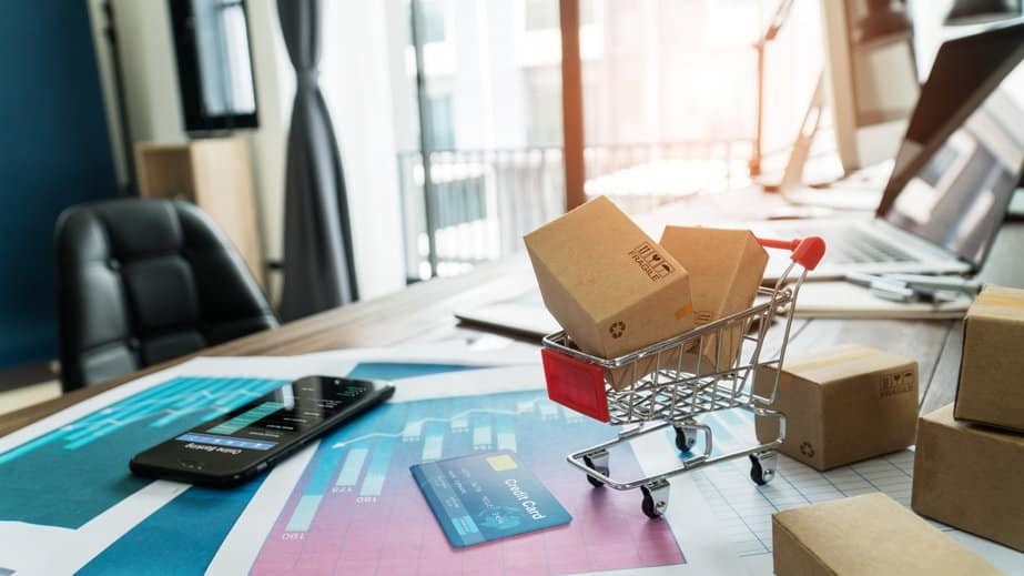 Petit chariot avec colis sur un bureau moderne avec cartes et smartphone