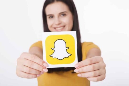 Femme souriante tenant un logo Snapchat
