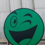Smiley vert faisant un clin d'œil devant un mur