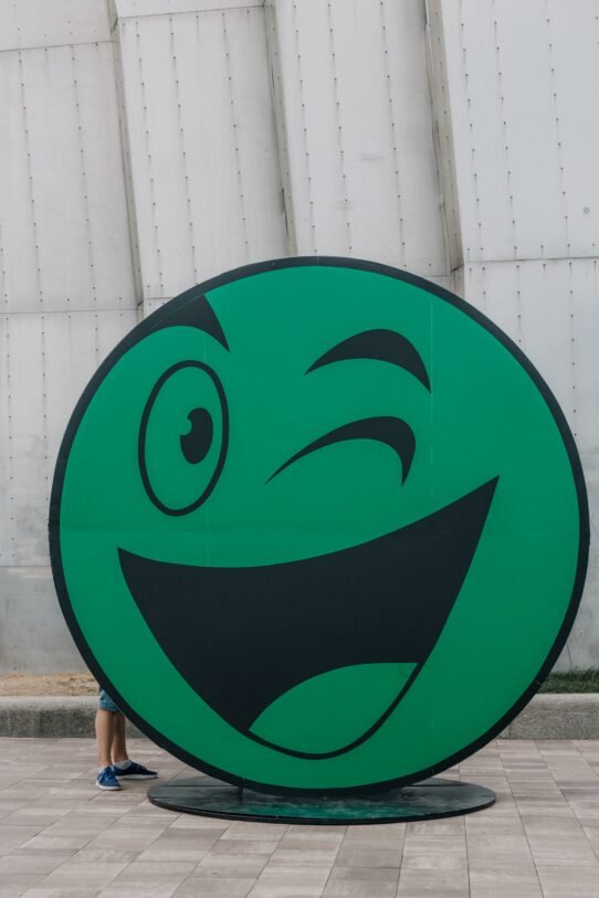 Smiley vert faisant un clin d'œil devant un mur
