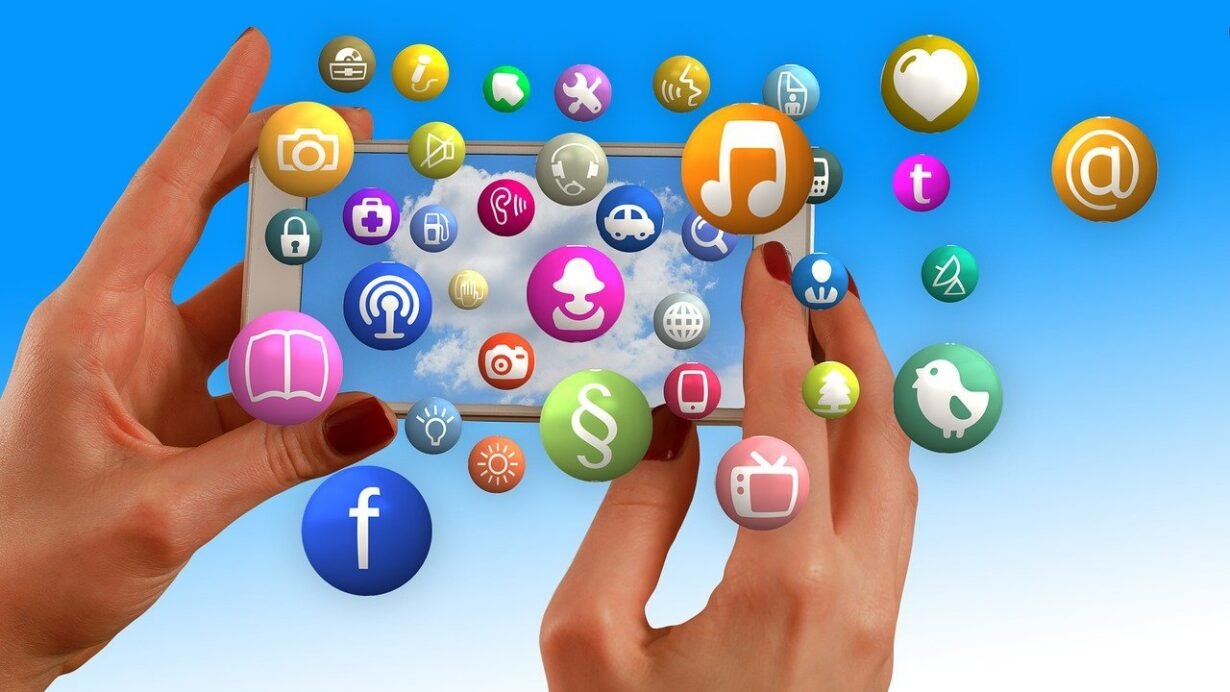 Mains tenant un smartphone entouré d'icônes d'applications