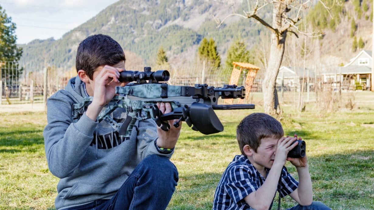 Deux enfants jouent en plein air avec des jumelles et un fusil jouet