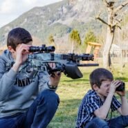 Deux enfants jouent en plein air avec des jumelles et un fusil jouet