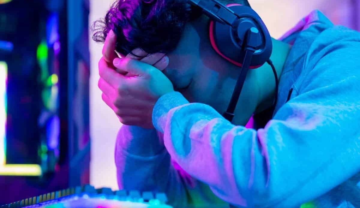 Gamer fatigué avec casque, tête dans les mains