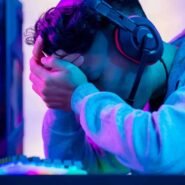 Gamer fatigué avec casque, tête dans les mains