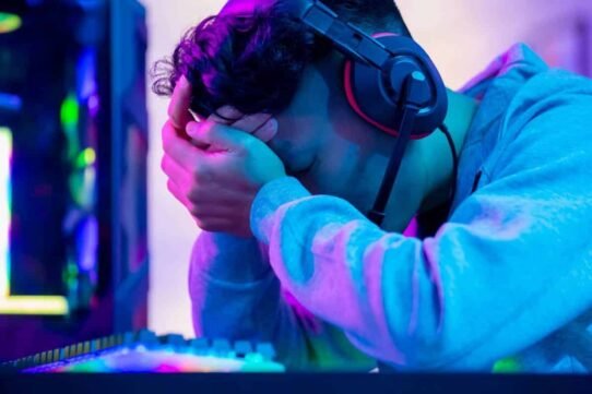Gamer fatigué avec casque, tête dans les mains