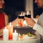 Couple trinquant au vin rouge lors d'un dîner aux chandelles