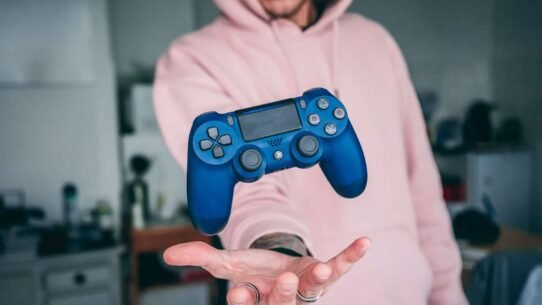 Manette de jeu bleue flottant au-dessus de la main d'une personne
