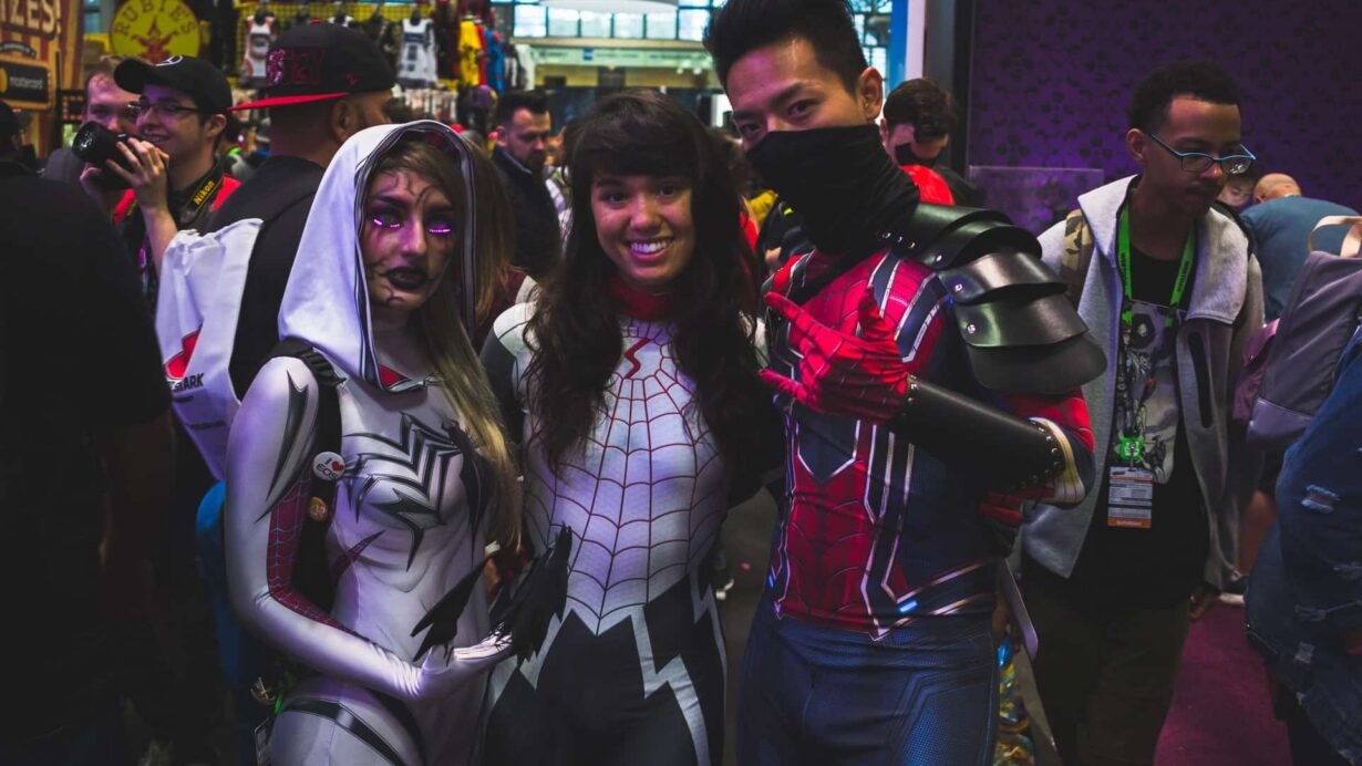 Trois personnes en costumes de super-héros à une convention de cosplay