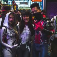 Trois personnes en costumes de super-héros à une convention de cosplay