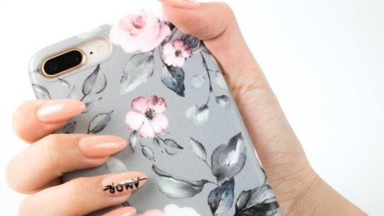Main tenant une coque de téléphone à motifs floraux roses et gris