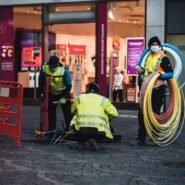 Techniciens installant des câbles à fibre optique devant un magasin