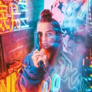 Femme avec un pistolet jouet dans des lumières néon colorées