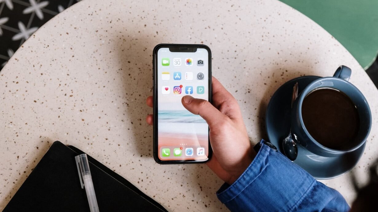 Personne utilisant un smartphone à côté d'une tasse de café