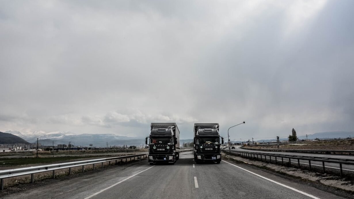 Deux camions IVECO roulant sur une autoroute sous un ciel nuageux