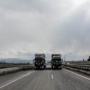 Deux camions IVECO roulant sur une autoroute sous un ciel nuageux
