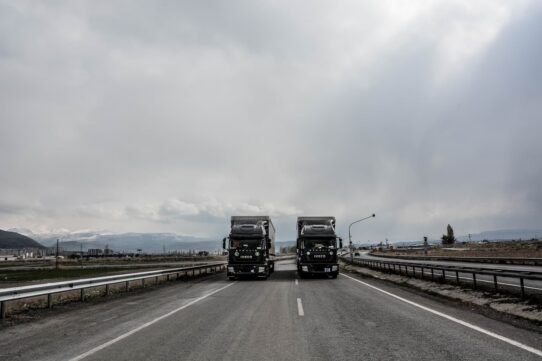 Deux camions IVECO roulant sur une autoroute sous un ciel nuageux