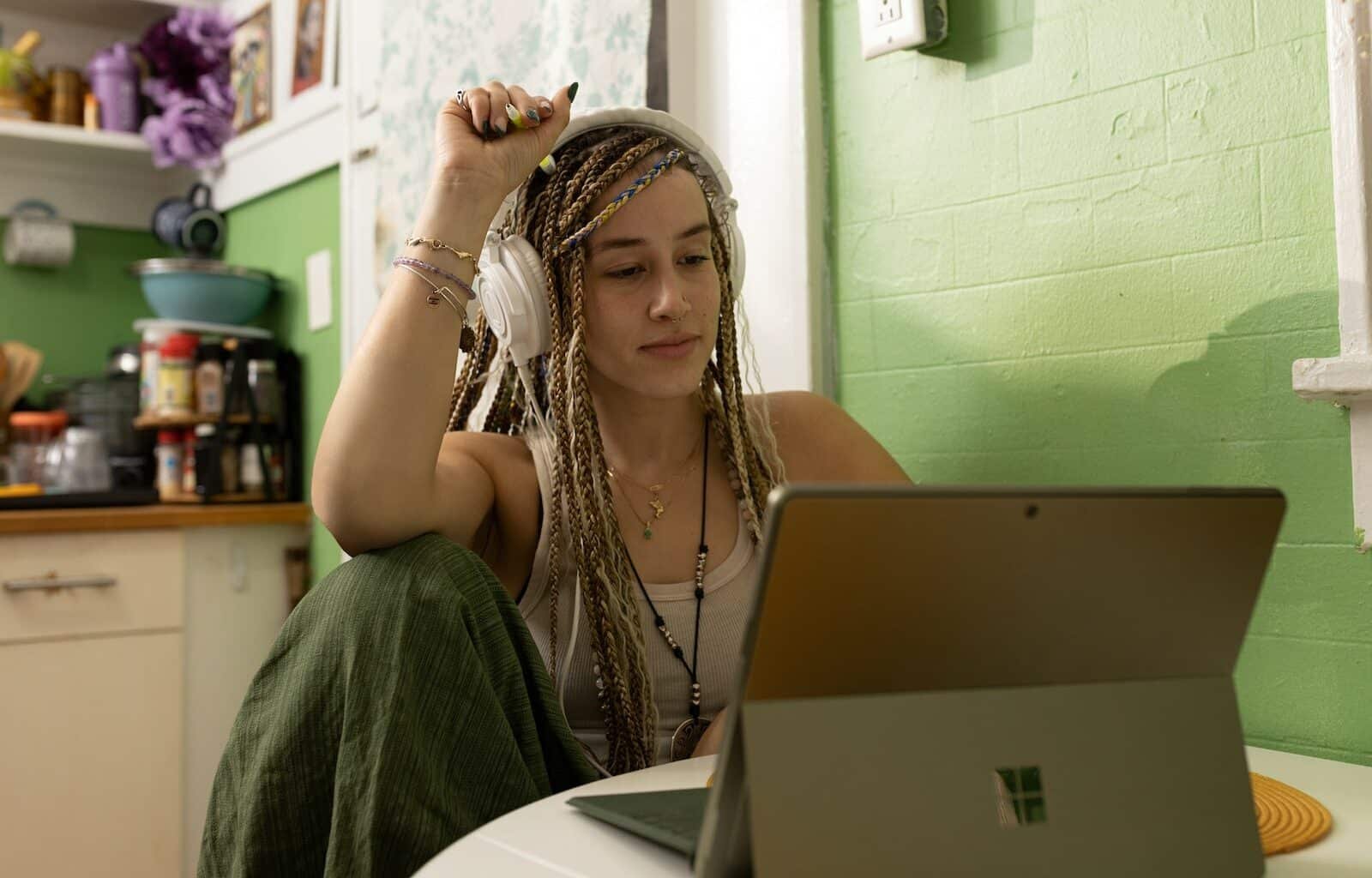a woman with dreadlocks sitting in front of a laptop computer