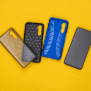 Trois étuis de smartphone colorés à côté d'un téléphone sur fond jaune