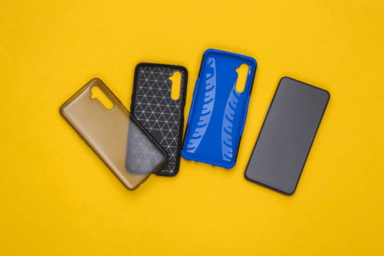 Trois étuis de smartphone colorés à côté d'un téléphone sur fond jaune