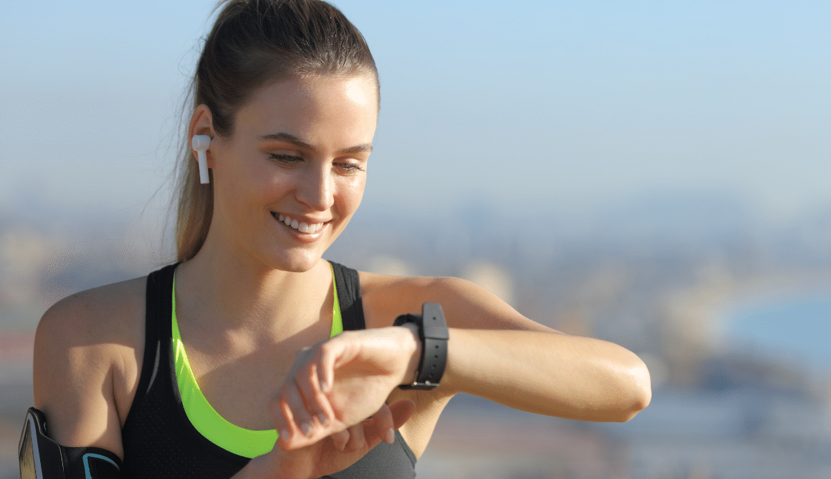 Femme souriante en tenue de sport utilisant une montre connectée