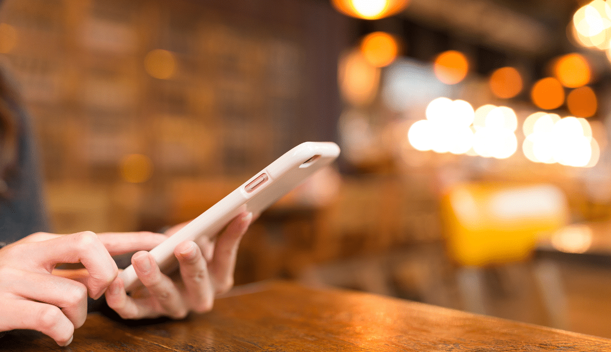 Personne utilisant un smartphone dans un café éclairé