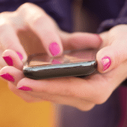 Personne utilisant un smartphone avec vernis à ongles rose